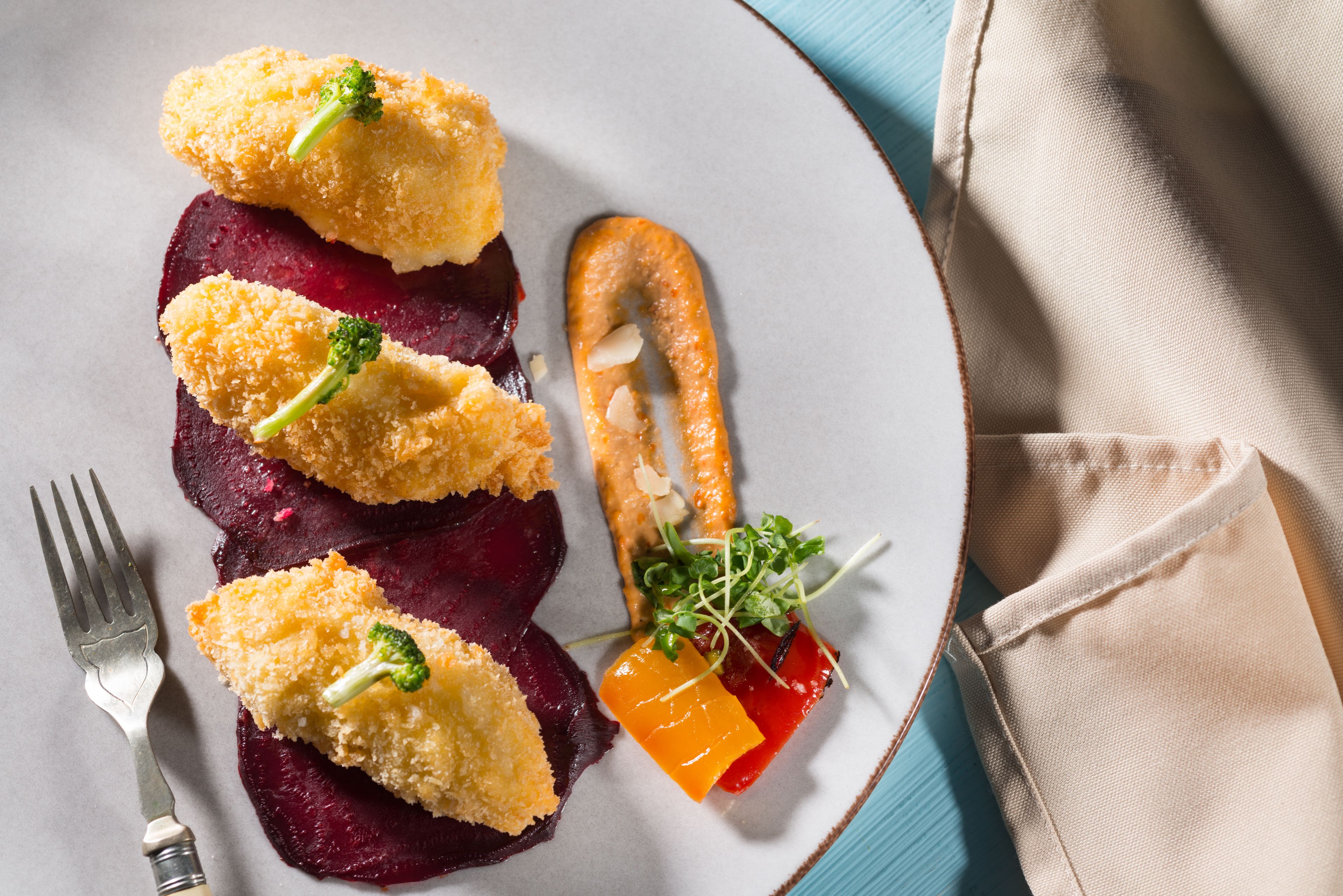 A plate with food items including breaded pieces, beet slices, and a vegetable skewer.