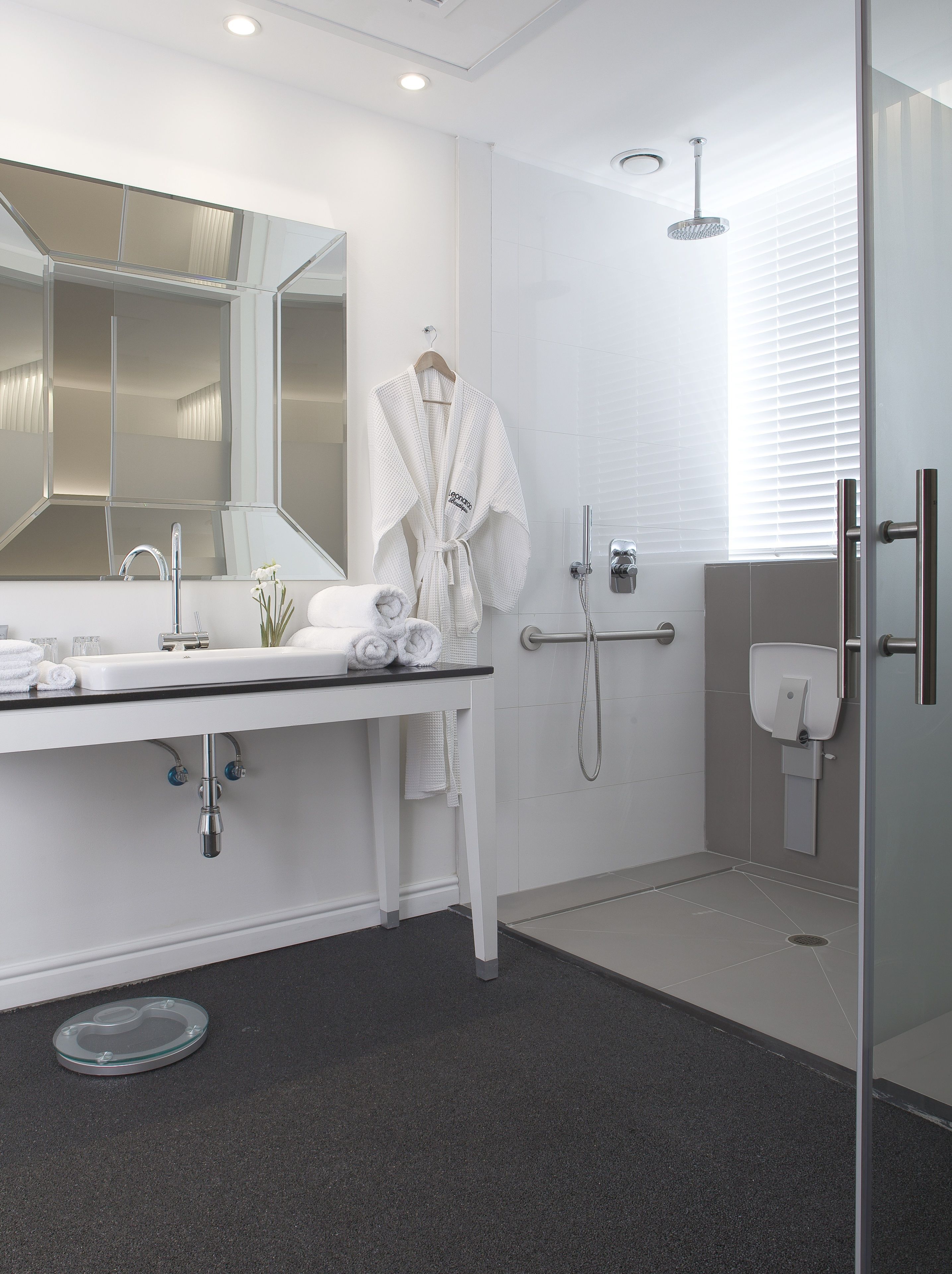 Un baño moderno con un espejo grande, un lavabo, una ducha y una puerta de vidrio.