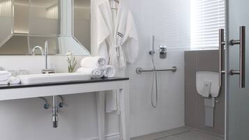 Un baño moderno con un espejo grande, un lavabo, una ducha y una puerta de vidrio.