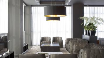 Een moderne zithoek met leren banken, een salontafel en een grote vloerlamp.