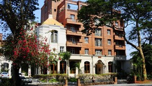 A multi-story building with a mix of brick and white facades, featuring balconies and arched windows.