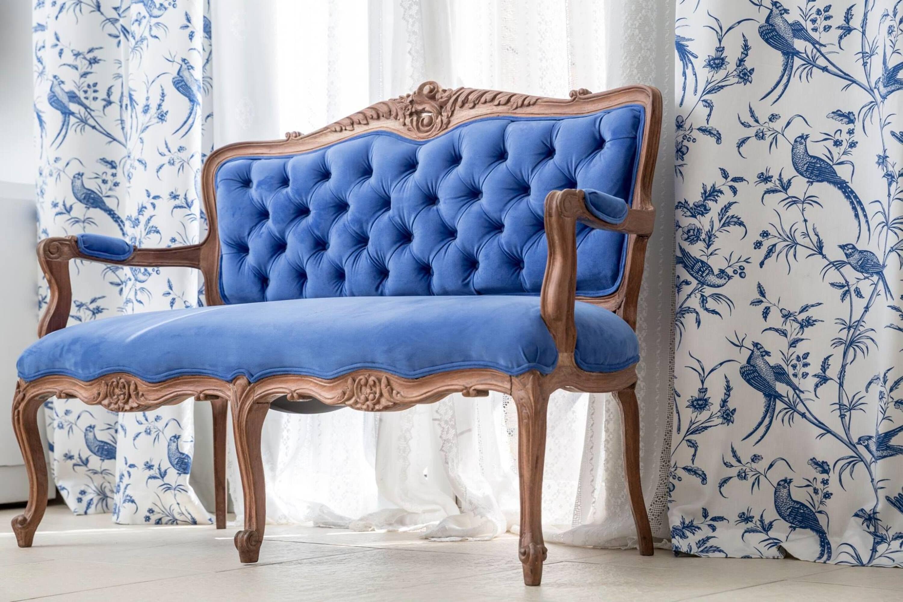 A blue upholstered chair with ornate wooden legs and a tufted backrest.