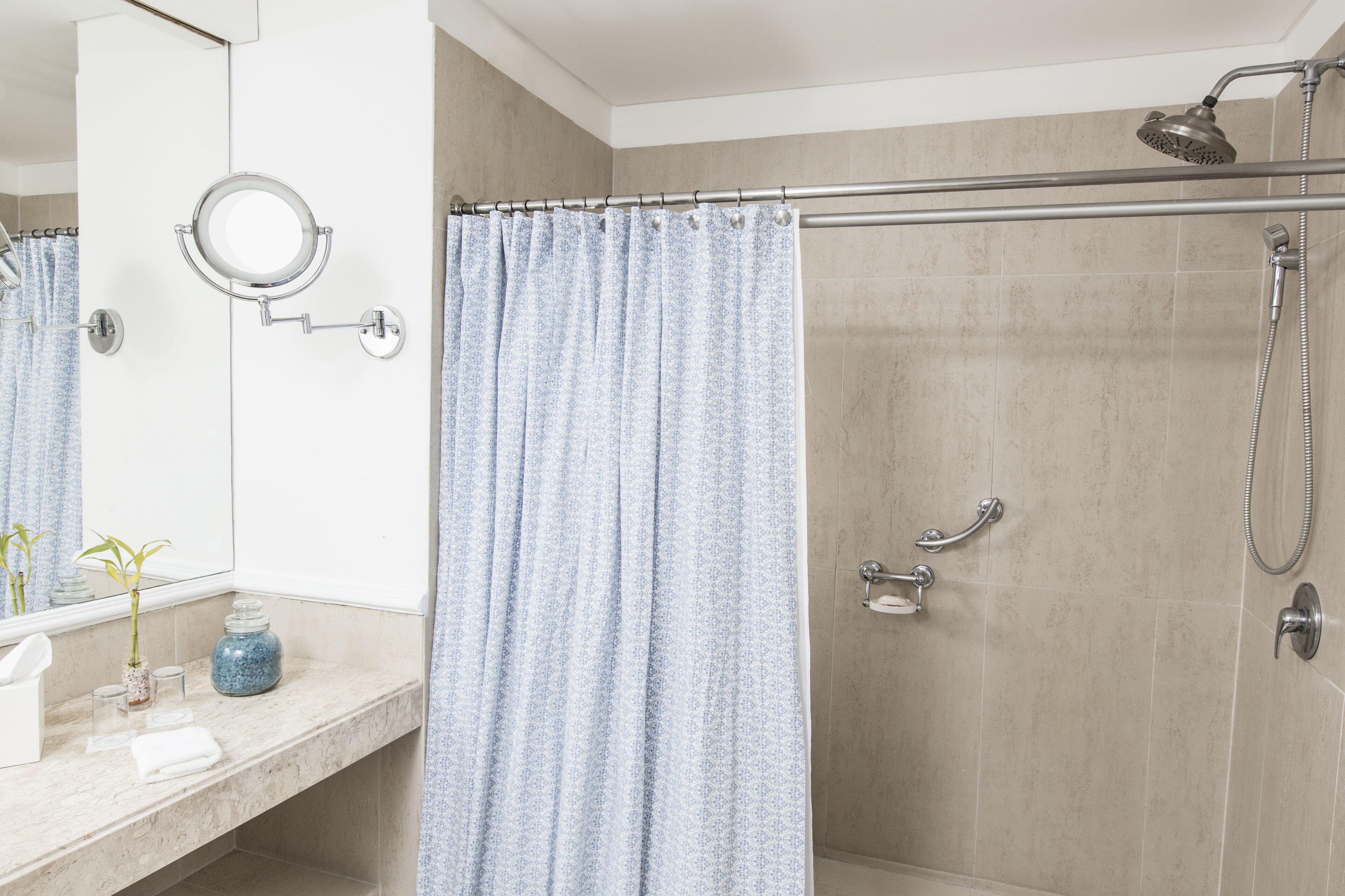 A bathroom with a shower, a toilet, a sink, a mirror, and a towel rack.