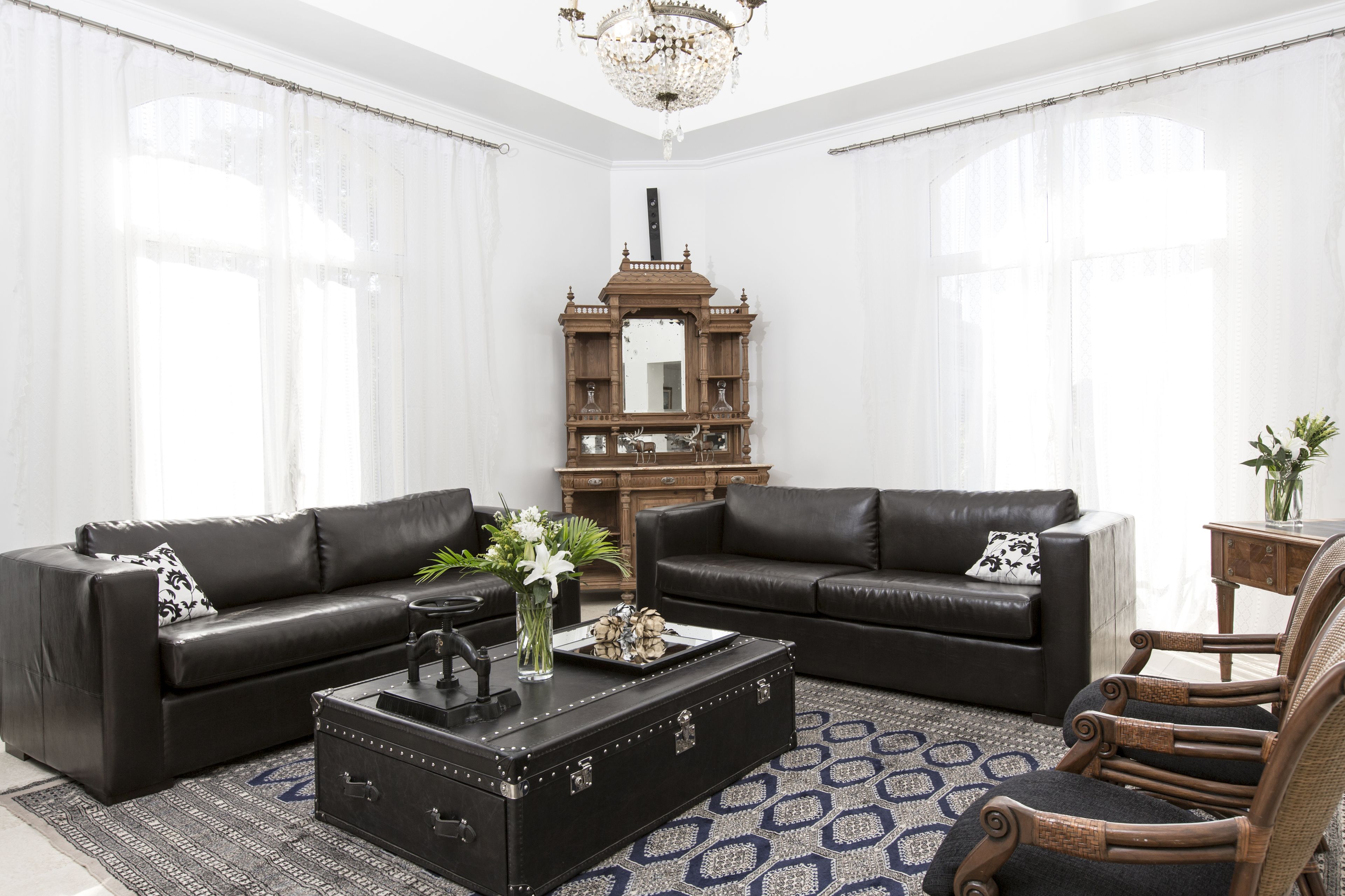 A living room with two black leather sofas, a wooden coffee table, and a wicker armchair.