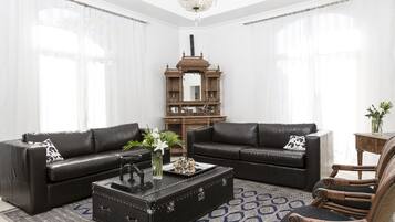 A living room with two black leather sofas, a wooden coffee table, and a wicker armchair.