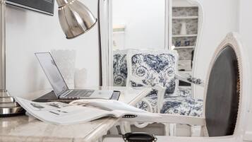 Un espace de travail comprenant un ordinateur portable, une lampe et une chaise avec un coussin à motifs.