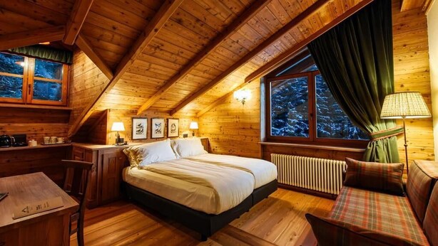 Ein gemütliches Schlafzimmer in einer Holzhütte, ausgestattet mit einem Bett, einem Schreibtisch, einem Sessel und einem Fenster mit Vorhängen.