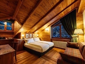 A cozy wooden cabin bedroom with a bed, a desk, a chair, and a window with curtains. - Hotel Breithorn (Ayas)