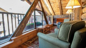 Ein gemütliches Zimmer mit Holzboden, einem grünen Sessel, einem Tisch und einer Lampe.