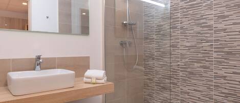 A modern bathroom with a rectangular sink, a glass shower enclosure, and a wooden vanity.