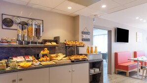 Un buffet della colazione con diversi cibi e un'area salotto con poltrone rosse imbottite.