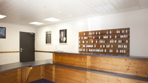 Zona de recepción con un mostrador de madera, una puerta oscura y una pared decorada con llaveros.