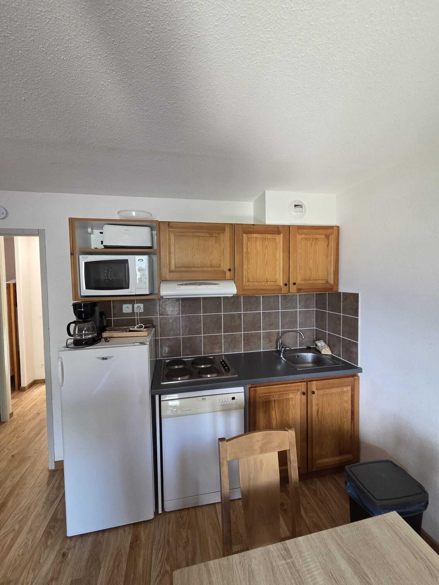 Una cocina compacta equipada con refrigerador, microondas, estufa y lavaplatos.