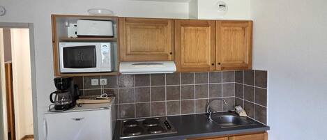 Una cocina compacta equipada con refrigerador, microondas, estufa y lavaplatos.