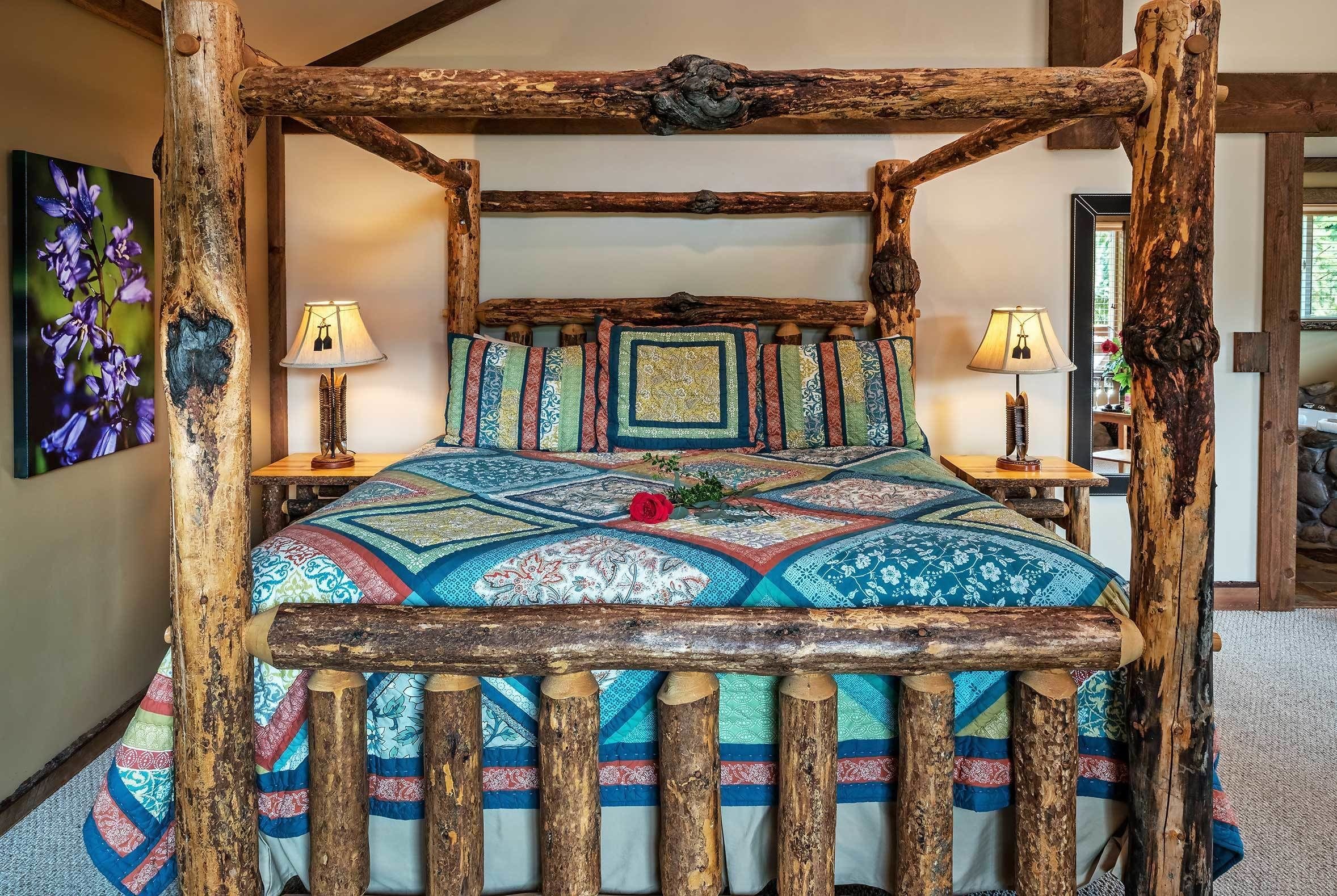 Un cadre de lit en bois rustique, agrémenté d’une courtepointe colorée et de deux lampes de chevet.