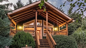A wooden cabin with a porch, stairs, and a sign indicating its name. - Carson Ridge Luxury Cabins (Carson)