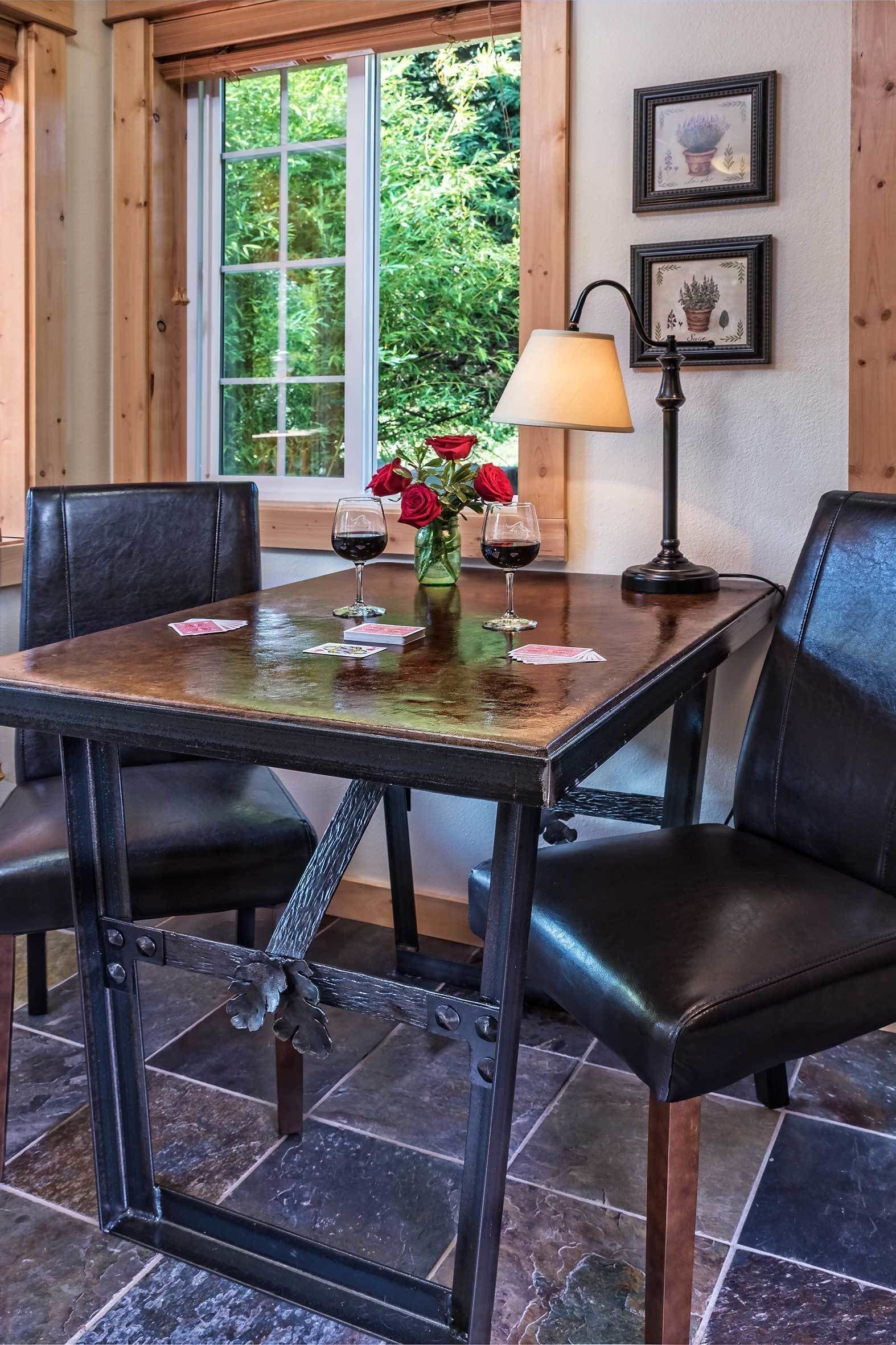 A dining table with chairs, a vase with flowers, and a wine glass.