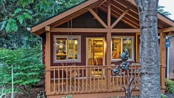 Une cabane dotée d’une terrasse en bois, de grandes fenêtres et d’un porche.