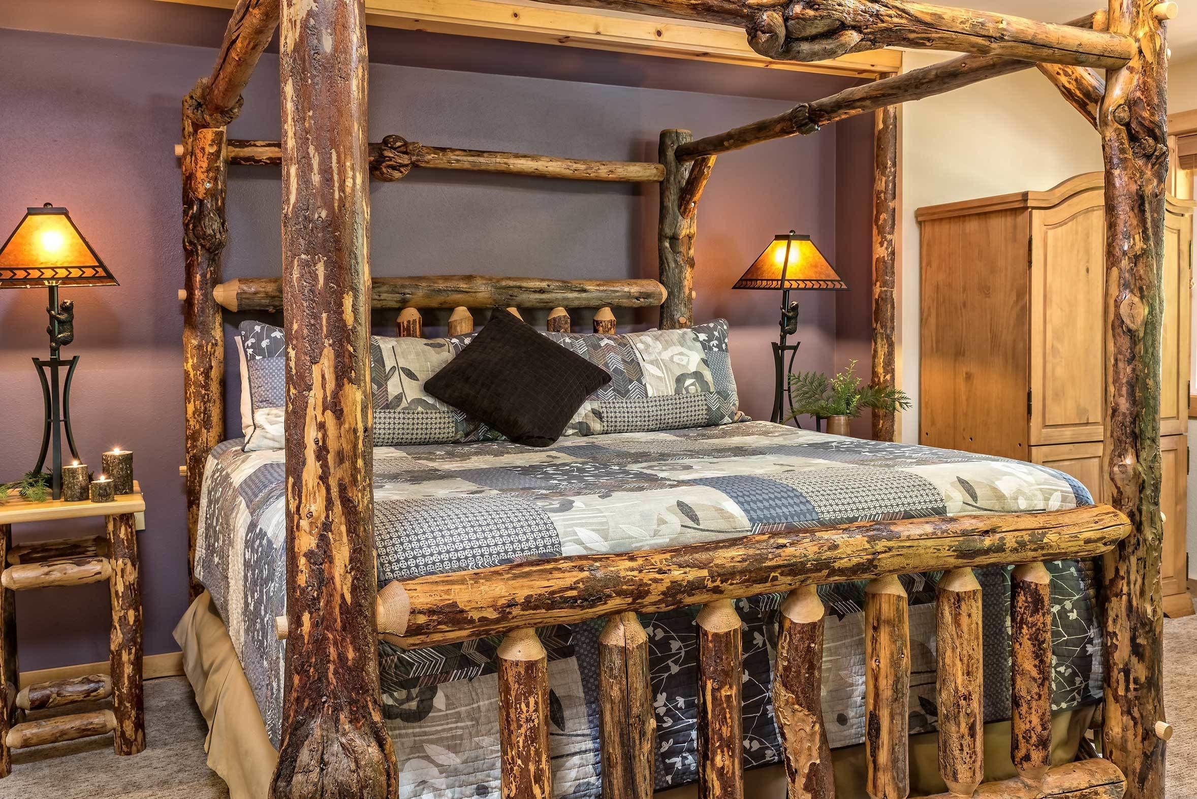 A rustic wooden four-poster bed with a patterned bedspread and two bedside lamps.