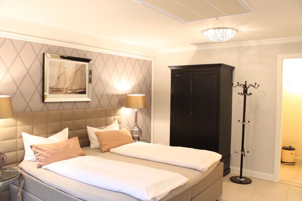 A hotel room with two beds, a large mirror, a wardrobe, and a floor lamp. - Hotel Villa Sommer (Bad Doberan)