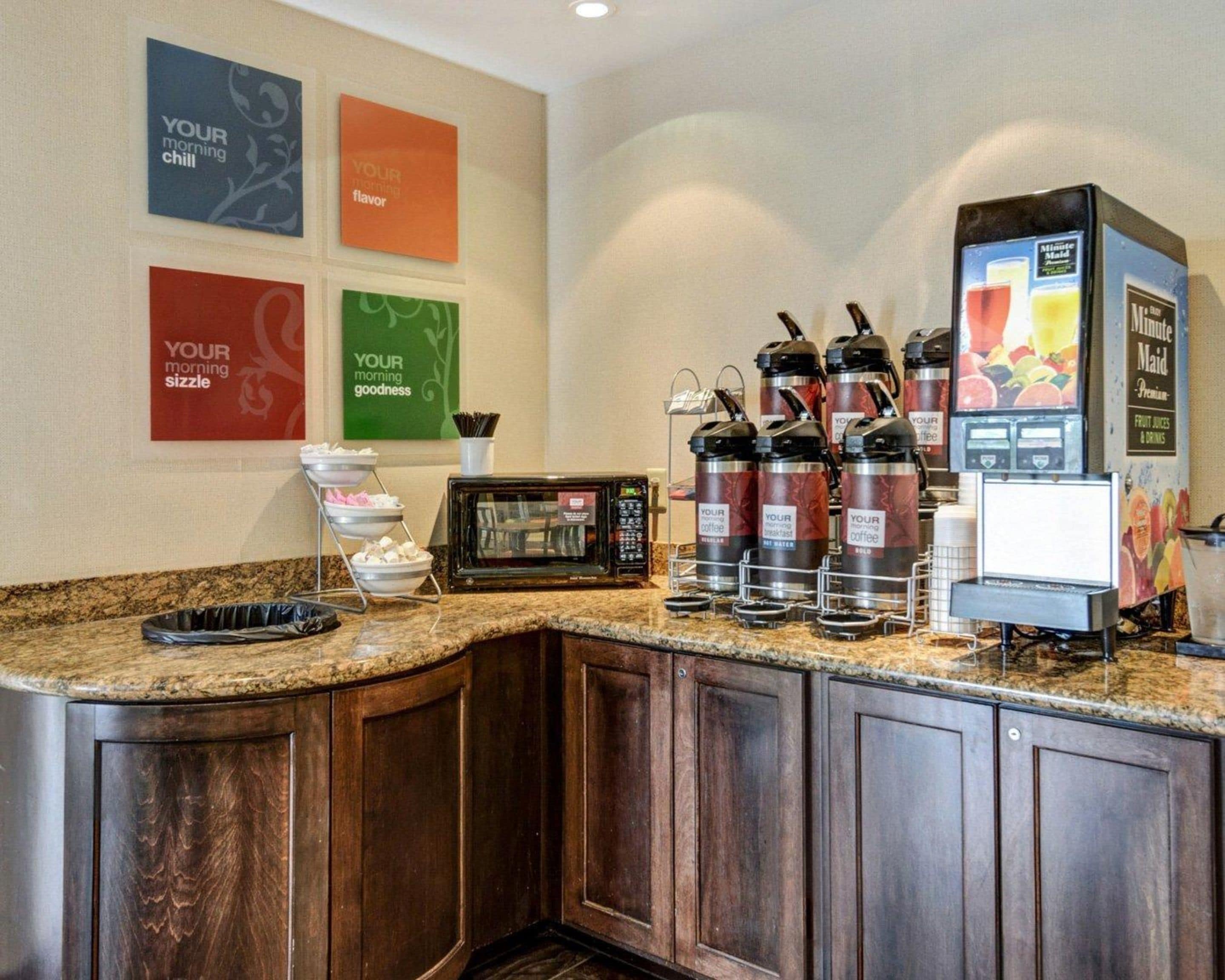 Una estación de café con varios dispensadores, un microondas y un refrigerador.