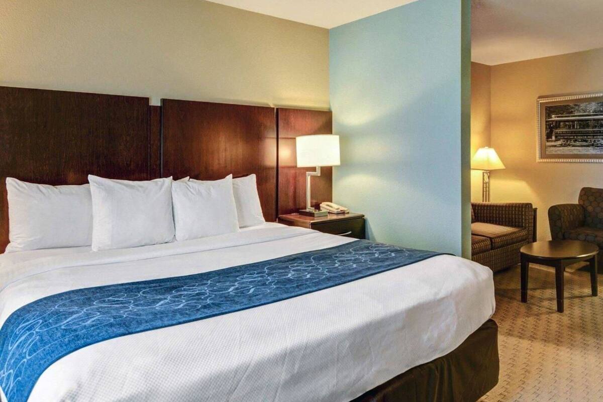 Une chambre d’hôtel avec un grand lit, une table de chevet, une lampe, une chaise et une petite table.