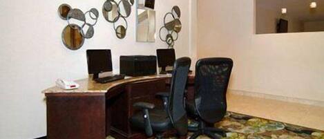 A conference room with a wooden desk, black office chairs, and a decorative mirror wall.