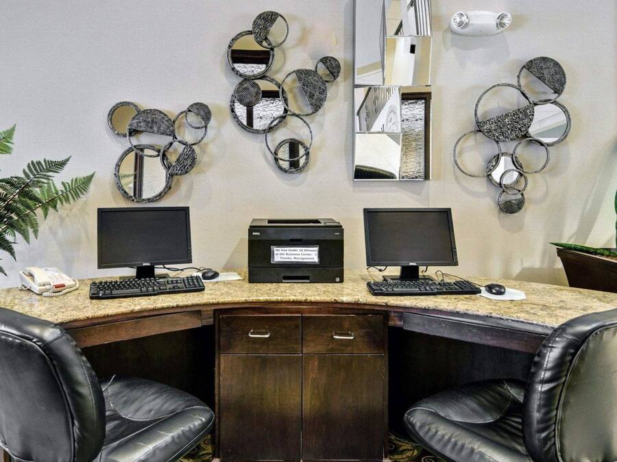 A workspace with two monitors, a printer, and a desk with a telephone.