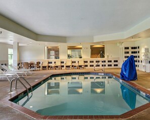 Un área de piscina con sillas de descanso, un vestuario y una zona de estar cubierta.
