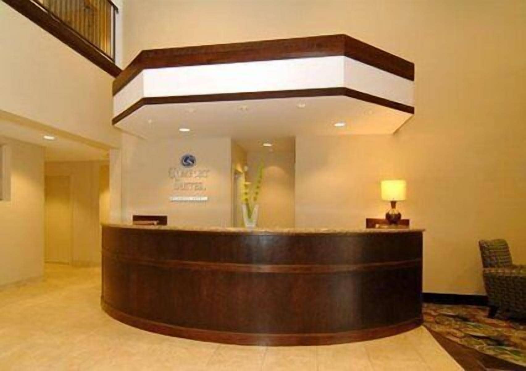 A reception desk with a wooden finish, a sign above it, and a lamp to the right.