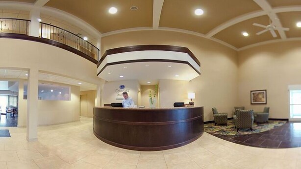 A hotel reception area with a curved reception desk, a receptionist, and a seating area with chairs. - Comfort Suites near Hot Springs Park (Hot Springs)