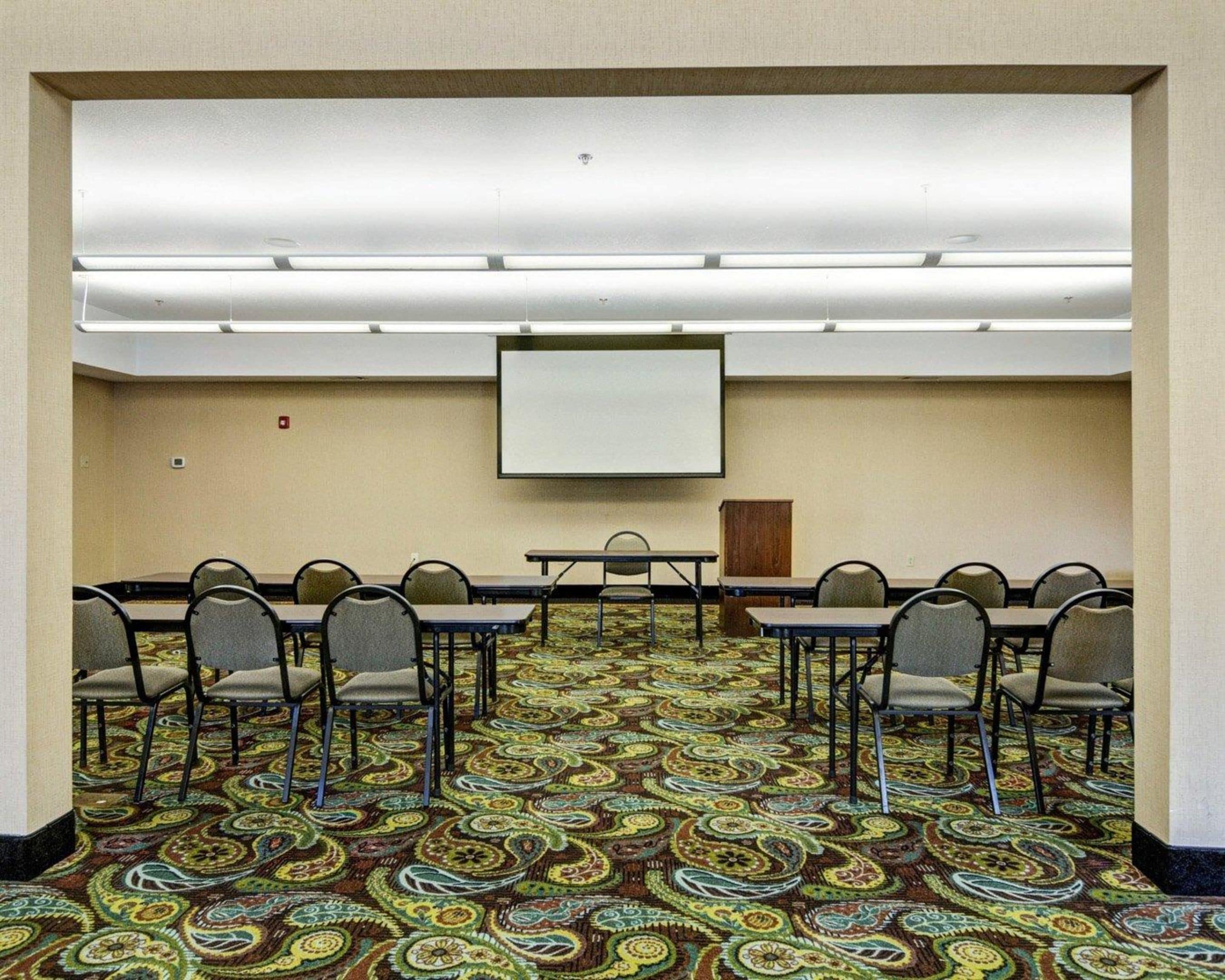 A conference room with a carpeted floor, a whiteboard, and a projector screen.