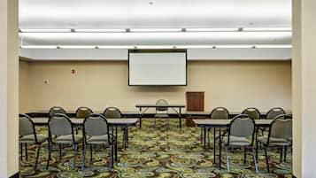 A conference room with a carpeted floor, a whiteboard, and a projector screen.