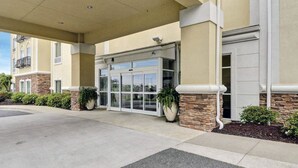 A hotel entrance with a covered walkway, stone pillars, and a glass door entrance. - Comfort Suites near Hot Springs Park (Hot Springs)
