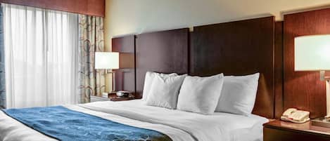 A hotel room with a large bed, a bedside table with a lamp, and a telephone.