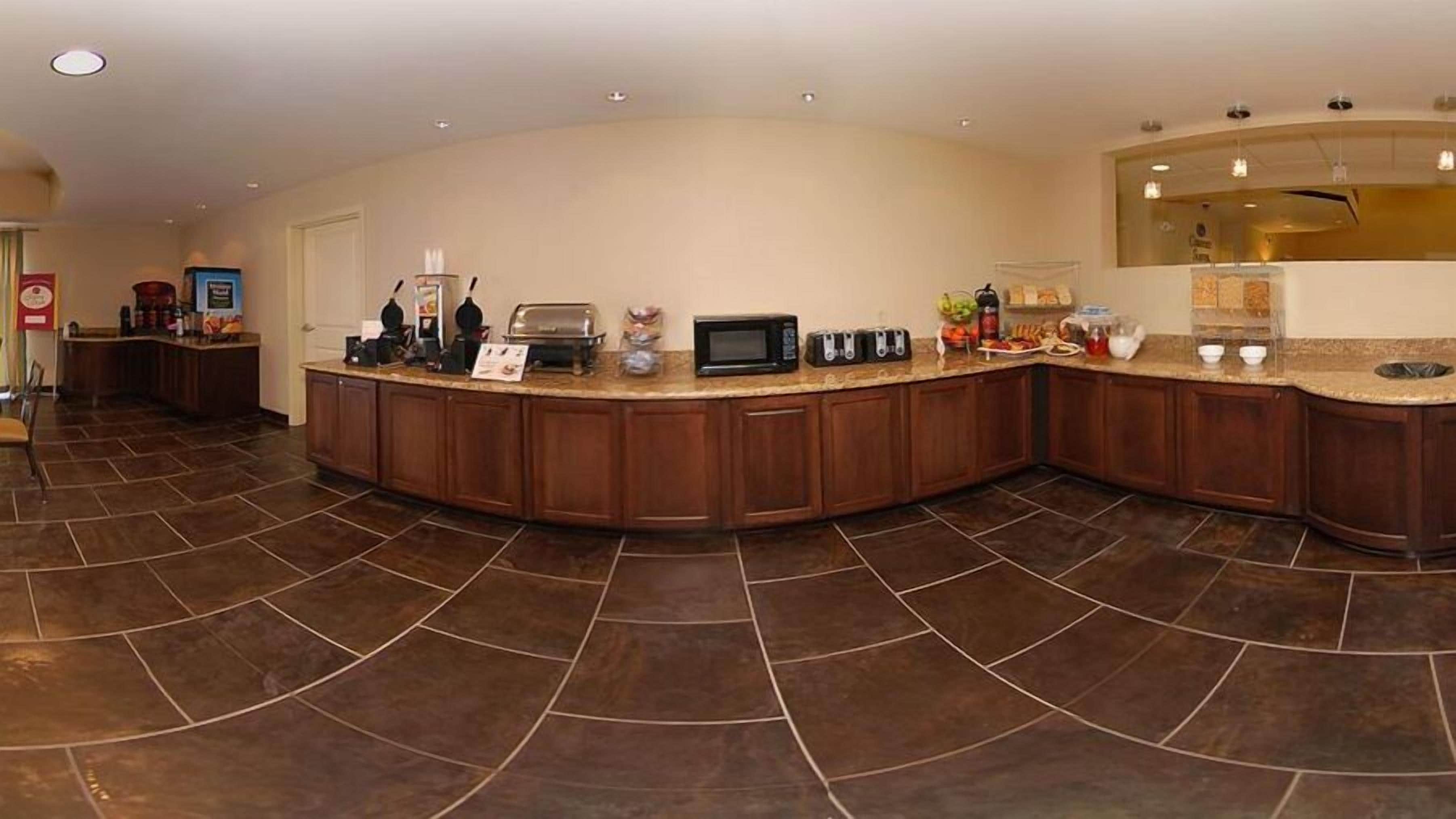 A spacious kitchen with a curved island, equipped with a microwave, toaster, and various appliances.