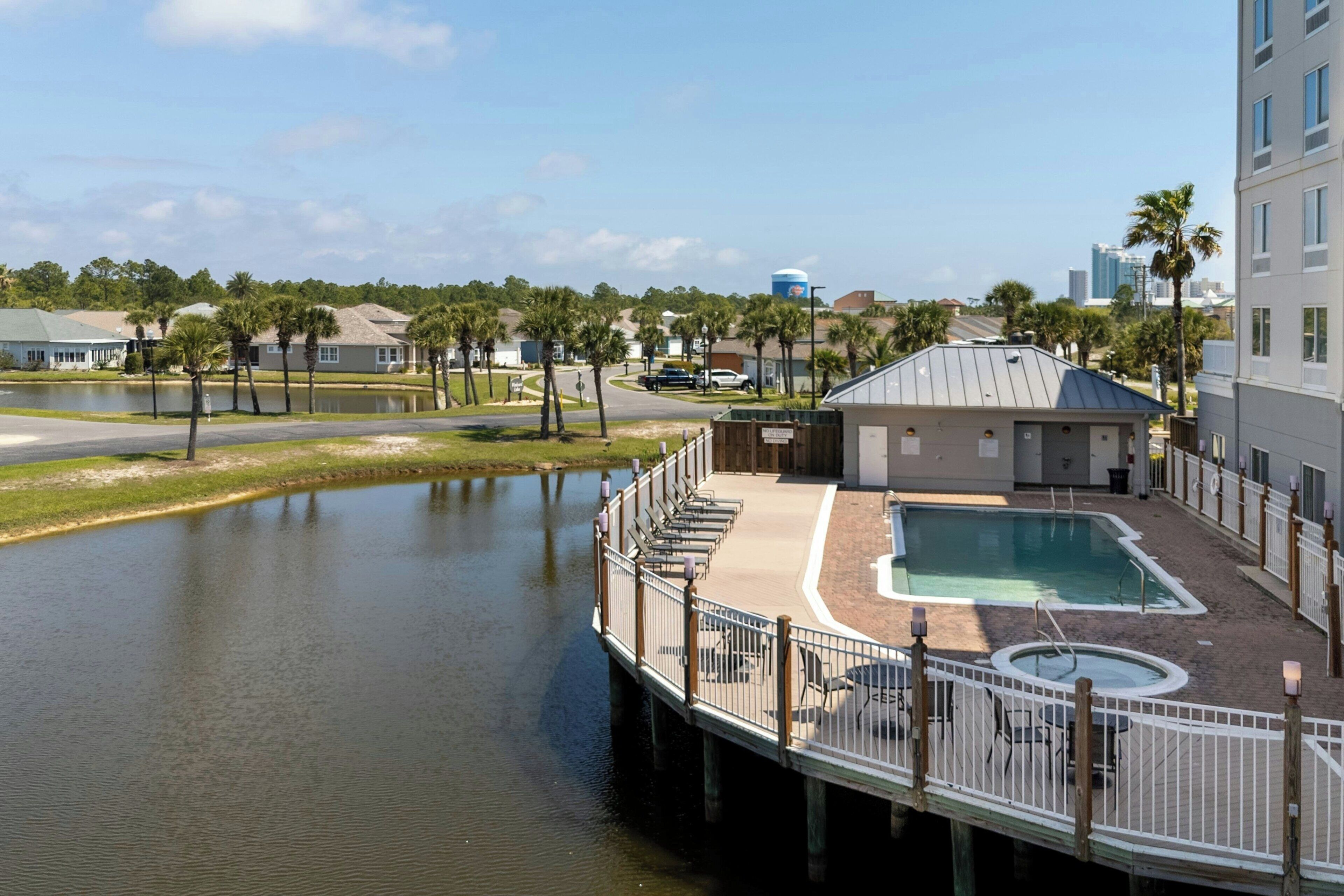 A waterfront hotel with a pool, a dock, and a view of the city skyline.