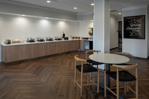 Una cocina moderna con salpicadero de azulejos blancos, armarios de madera y una estación de café integrada.