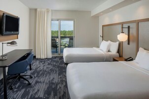 Une chambre d’hôtel avec deux lits, un bureau, une télévision et un balcon avec vue.