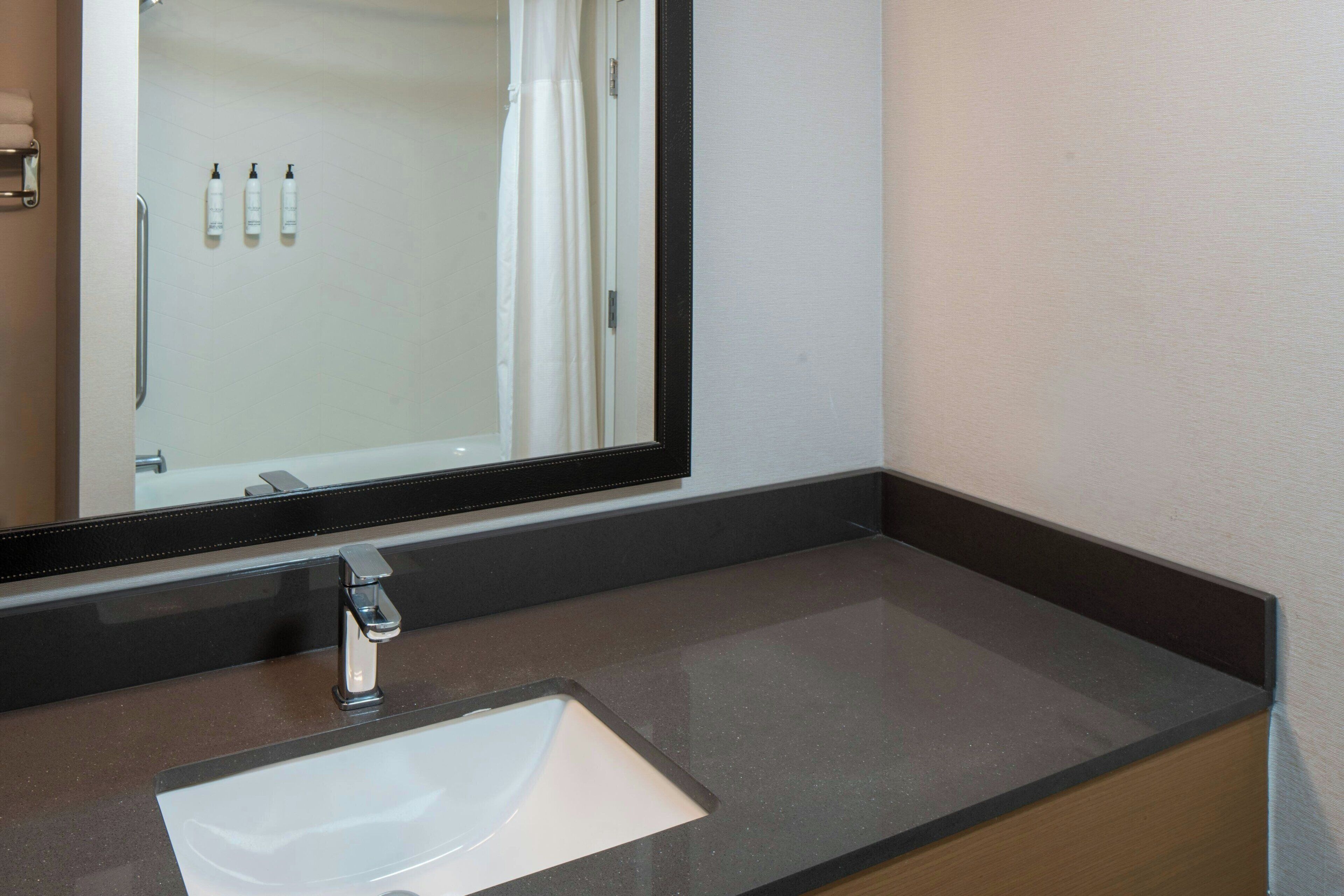 A bathroom with a sink, mirror, and toiletries.