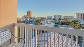 Un balcón con vista a un paisaje urbano, que incluye edificios y palmeras.