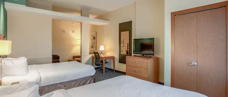 A hotel room with two beds, a desk, a television, and a wardrobe.