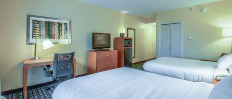 A hotel room with two beds, a desk with a lamp, a chair, a dresser, a television, and a microwave.