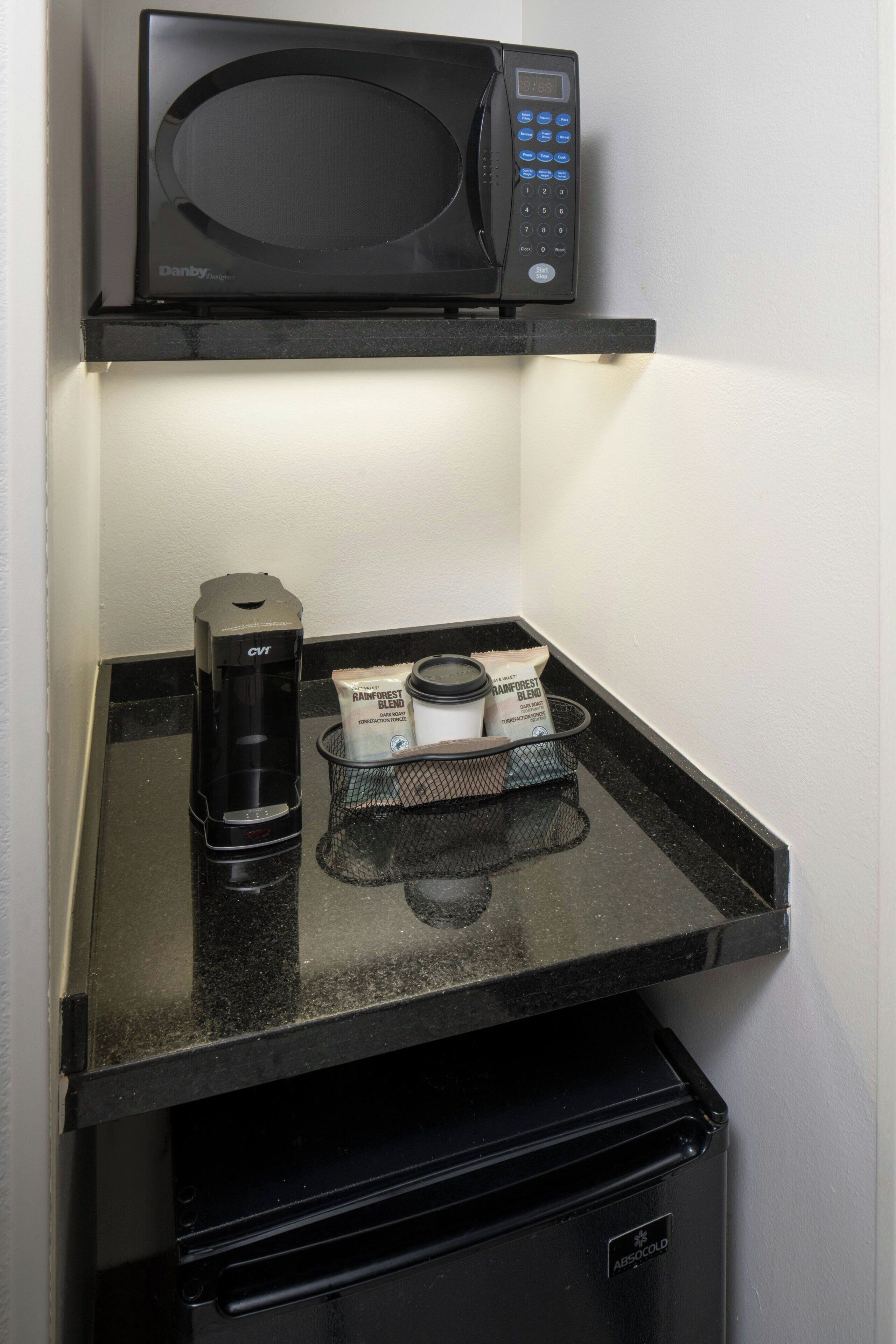 A microwave above a countertop with a coffee maker and two packets of coffee.