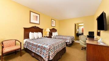 A hotel room with two beds, a desk, a chair, and a television.