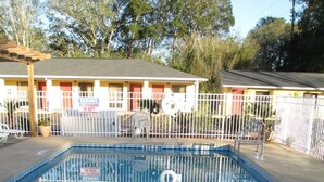 A rectangular pool with a depth of 3 feet 2 inches, surrounded by a white fence and a building with a red roof in the background.