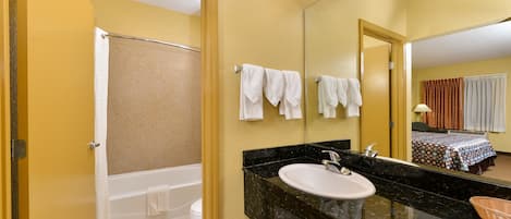 A bathroom with a bathtub, a sink, and a mirror.