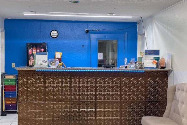A reception area with a blue wall, a brown decorative panel, a counter with various items, and a beige chair.