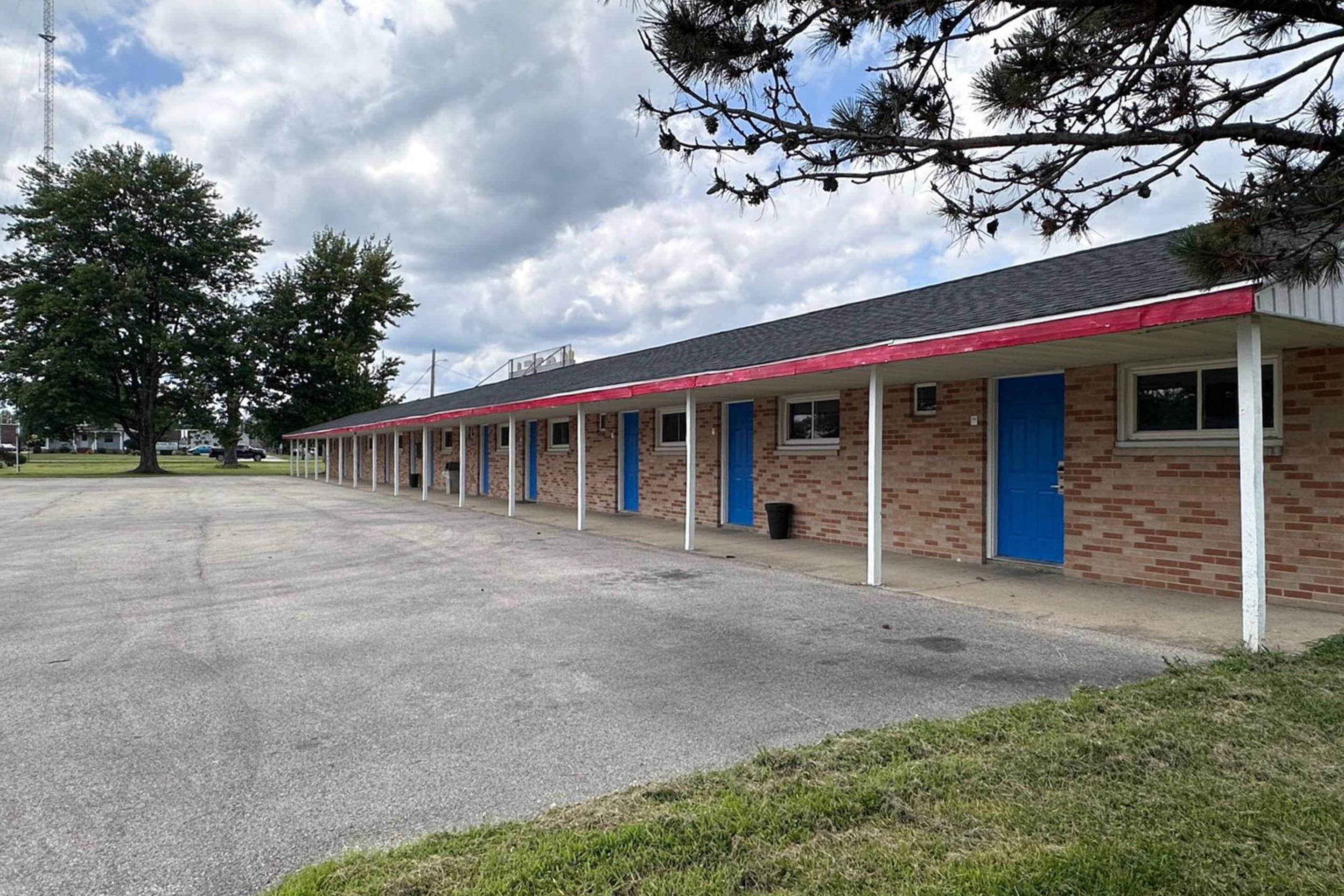 A motel with a row of rooms, each with a blue door and a small window.