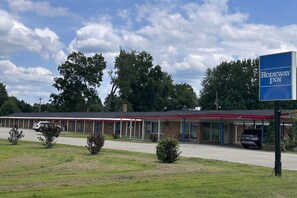 A motel with a signboard, a covered parking area, and a building with a red roof.